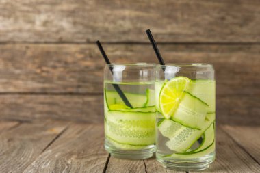 Salatalık suyu, limon, nane ve ahşap bir masada. İçme bardağında dilimlenmiş salatalık ile karıştırılmış su. Tonik ferahlatıcı bir içecek. Salatalık limonata. Doğal soğutma içeceği. Boşluğu kopyala.