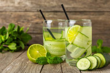 Salatalık suyu, limon, nane ve ahşap bir masada. İçme bardağında dilimlenmiş salatalık ile karıştırılmış su. Tonik ferahlatıcı bir içecek. Salatalık limonata. Doğal soğutma içeceği. Boşluğu kopyala.