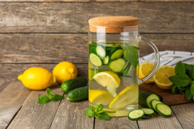 Salatalık suyu, limon, nane ve ahşap bir masada. İçme bardağında dilimlenmiş salatalık ile karıştırılmış su. Tonik ferahlatıcı bir içecek. Salatalık limonata. Doğal soğutma içeceği. Boşluğu kopyala.