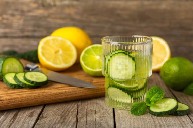 Salatalık suyu, limon, nane ve ahşap bir masada. İçme bardağında dilimlenmiş salatalık ile karıştırılmış su. Tonik ferahlatıcı bir içecek. Salatalık limonata. Doğal soğutma içeceği. Boşluğu kopyala.