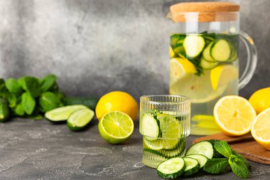 Salatalık suyu, limon, nane ve ahşap bir masada. İçme bardağında dilimlenmiş salatalık ile karıştırılmış su. Tonik ferahlatıcı bir içecek. Salatalık limonata. Doğal soğutma içeceği. Boşluğu kopyala.