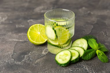 Salatalık suyu, limon, nane ve ahşap bir masada. İçme bardağında dilimlenmiş salatalık ile karıştırılmış su. Tonik ferahlatıcı bir içecek. Salatalık limonata. Doğal soğutma içeceği. Boşluğu kopyala.