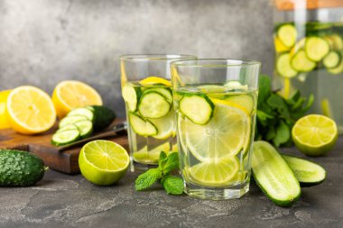 Salatalık suyu, limon, nane ve ahşap bir masada. İçme bardağında dilimlenmiş salatalık ile karıştırılmış su. Tonik ferahlatıcı bir içecek. Salatalık limonata. Doğal soğutma içeceği. Boşluğu kopyala.
