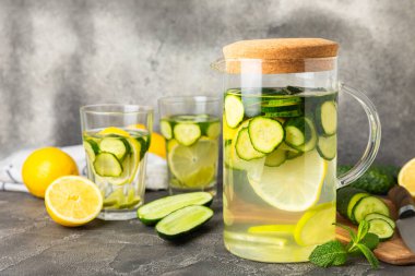 Salatalık suyu, limon, nane ve ahşap bir masada. İçme bardağında dilimlenmiş salatalık ile karıştırılmış su. Tonik ferahlatıcı bir içecek. Salatalık limonata. Doğal soğutma içeceği. Boşluğu kopyala.