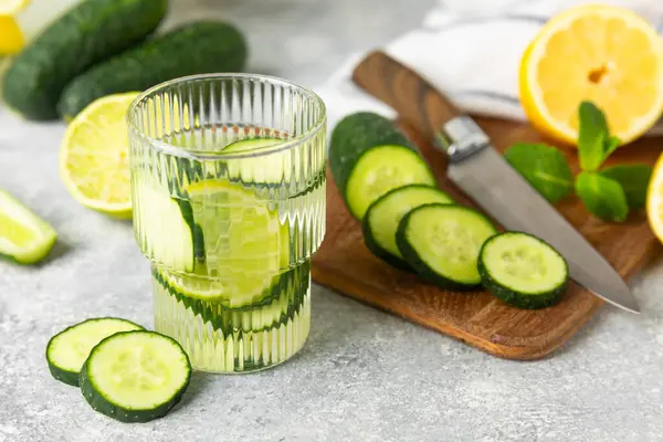 Salatalık suyu, limon, nane ve ahşap bir masada. İçme bardağında dilimlenmiş salatalık ile karıştırılmış su. Tonik ferahlatıcı bir içecek. Salatalık limonata. Doğal soğutma içeceği. Boşluğu kopyala.