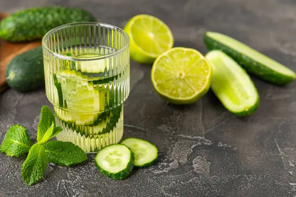 Salatalık suyu, limon, nane ve ahşap bir masada. İçme bardağında dilimlenmiş salatalık ile karıştırılmış su. Tonik ferahlatıcı bir içecek. Salatalık limonata. Doğal soğutma içeceği. Boşluğu kopyala.