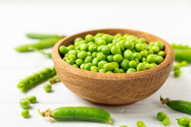 Ahşap zemin üzerinde yeşil bezelyeler olan taze bezelye kabukları. Tatlı yeşil bezelyeler. Yeşil bezelye fasulyesi sebzesi. Vejetaryen. Sağlıklı sebze. Boşluğu kopyala