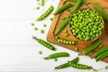 Ahşap zemin üzerinde yeşil bezelyeler olan taze bezelye kabukları. Tatlı yeşil bezelyeler. Yeşil bezelye fasulyesi sebzesi. Vejetaryen. Sağlıklı sebze. Boşluğu kopyala