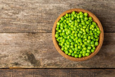 Ahşap zemin üzerinde yeşil bezelyeler olan taze bezelye kabukları. Tatlı yeşil bezelyeler. Yeşil bezelye fasulyesi sebzesi. Vejetaryen. Sağlıklı sebze. Boşluğu kopyala