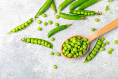 Ahşap zemin üzerinde yeşil bezelyeler olan taze bezelye kabukları. Tatlı yeşil bezelyeler. Yeşil bezelye fasulyesi sebzesi. Vejetaryen. Sağlıklı sebze. Boşluğu kopyala