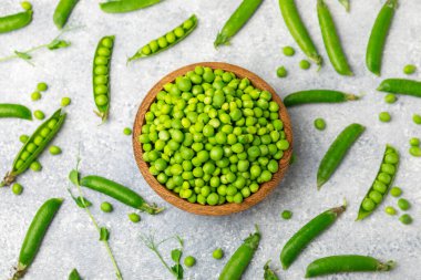 Ahşap zemin üzerinde yeşil bezelyeler olan taze bezelye kabukları. Tatlı yeşil bezelyeler. Yeşil bezelye fasulyesi sebzesi. Vejetaryen. Sağlıklı sebze. Boşluğu kopyala