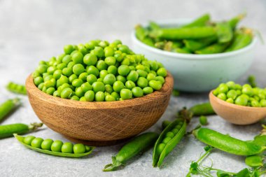 Ahşap zemin üzerinde yeşil bezelyeler olan taze bezelye kabukları. Tatlı yeşil bezelyeler. Yeşil bezelye fasulyesi sebzesi. Vejetaryen. Sağlıklı sebze. Boşluğu kopyala