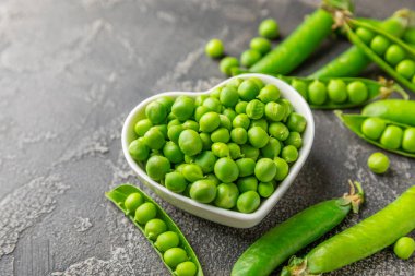 Ahşap zemin üzerinde yeşil bezelyeler olan taze bezelye kabukları. Tatlı yeşil bezelyeler. Yeşil bezelye fasulyesi sebzesi. Vejetaryen. Sağlıklı sebze. Boşluğu kopyala