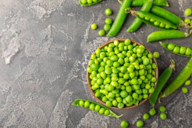 Ahşap zemin üzerinde yeşil bezelyeler olan taze bezelye kabukları. Tatlı yeşil bezelyeler. Yeşil bezelye fasulyesi sebzesi. Vejetaryen. Sağlıklı sebze. Boşluğu kopyala