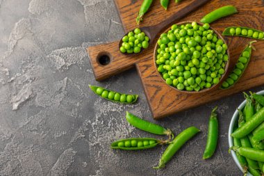 Ahşap zemin üzerinde yeşil bezelyeler olan taze bezelye kabukları. Tatlı yeşil bezelyeler. Yeşil bezelye fasulyesi sebzesi. Vejetaryen. Sağlıklı sebze. Boşluğu kopyala