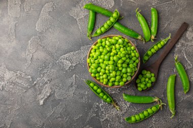 Ahşap zemin üzerinde yeşil bezelyeler olan taze bezelye kabukları. Tatlı yeşil bezelyeler. Yeşil bezelye fasulyesi sebzesi. Vejetaryen. Sağlıklı sebze. Boşluğu kopyala