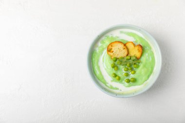 Ahşap bir masada yeşil bezelye çorbası. Taze bezelye çorbası kasesi. Yeşil bezelye ve kızarmış ekmekle dolu bir kasede lezzetli, sağlıklı krema çorbası. Sağlıklı vejetaryen püresi. Uzayı kopyala Metin için boşluk.