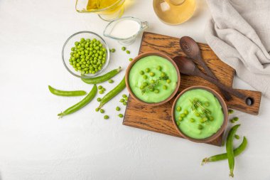 Ahşap bir masada yeşil bezelye çorbası. Taze bezelye çorbası kasesi. Yeşil bezelye ve kızarmış ekmekle dolu bir kasede lezzetli, sağlıklı krema çorbası. Sağlıklı vejetaryen püresi. Uzayı kopyala Metin için boşluk.