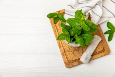 Ahşap zemin üzerinde havan ve kabuk ile taze nane. Melissa gider. Şifalı bitkiler, ilaç için havanda yeşil nane yaprakları. Mesaj için alan. Boşluğu kopyala.