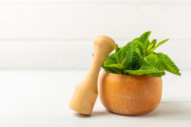 Ahşap zemin üzerinde havan ve kabuk ile taze nane. Melissa gider. Şifalı bitkiler, ilaç için havanda yeşil nane yaprakları. Mesaj için alan. Boşluğu kopyala.