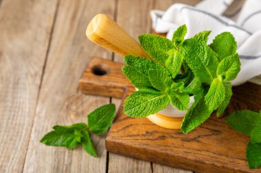 Ahşap zemin üzerinde havan ve kabuk ile taze nane. Melissa gider. Şifalı bitkiler, ilaç için havanda yeşil nane yaprakları. Mesaj için alan. Boşluğu kopyala.