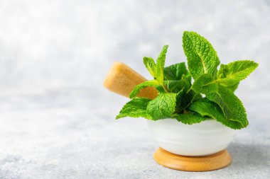 Ahşap zemin üzerinde havan ve kabuk ile taze nane. Melissa gider. Şifalı bitkiler, ilaç için havanda yeşil nane yaprakları. Mesaj için alan. Boşluğu kopyala.