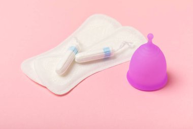 Aybaşı bardağı parlak bir arka planda. Hijyenik peçeteler, tamponlar ve regl kupası. Kritik günler, regl dönemi kavramı. Kadın hijyen ürünü. Kadın sağlığı kavramı. Adet öncesi sendromu. Boşluğu kopyala