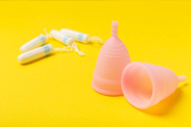 Aybaşı bardağı parlak bir arka planda. Hijyenik peçeteler, tamponlar ve regl kupası. Kritik günler, regl dönemi kavramı. Kadın hijyen ürünü. Kadın sağlığı kavramı. Adet öncesi sendromu. Boşluğu kopyala