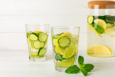 Salatalık suyu, limon, nane ve ahşap bir masada. İçme bardağında dilimlenmiş salatalık ile karıştırılmış su. Tonik ferahlatıcı bir içecek. Salatalık limonata. Doğal soğutma içeceği. Boşluğu kopyala.