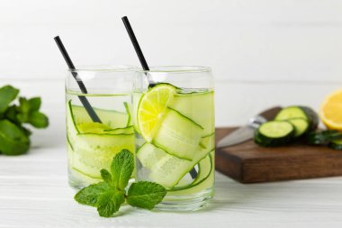 Salatalık suyu, limon, nane ve ahşap bir masada. İçme bardağında dilimlenmiş salatalık ile karıştırılmış su. Tonik ferahlatıcı bir içecek. Salatalık limonata. Doğal soğutma içeceği. Boşluğu kopyala.