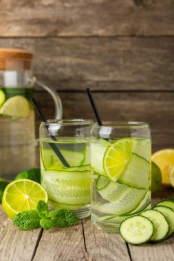 Salatalık suyu, limon, nane ve ahşap bir masada. İçme bardağında dilimlenmiş salatalık ile karıştırılmış su. Tonik ferahlatıcı bir içecek. Salatalık limonata. Doğal soğutma içeceği. Boşluğu kopyala.