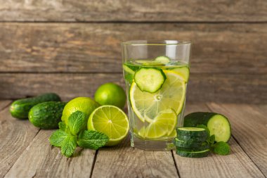 Salatalık suyu, limon, nane ve ahşap bir masada. İçme bardağında dilimlenmiş salatalık ile karıştırılmış su. Tonik ferahlatıcı bir içecek. Salatalık limonata. Doğal soğutma içeceği. Boşluğu kopyala.