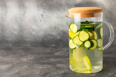 Salatalık suyu, limon, nane ve ahşap bir masada. İçme bardağında dilimlenmiş salatalık ile karıştırılmış su. Tonik ferahlatıcı bir içecek. Salatalık limonata. Doğal soğutma içeceği. Boşluğu kopyala.