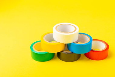 Parlak renkli arka plandaki bant yalıtılıyor. Farklı renkte izolasyon bantları. Yalıtım bandı. İnşaat aletleri. Elektrikçi aletleri. Bir parça koli bandı. Metin için boşluk. Boşluğu kopyala.