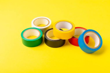 Parlak renkli arka plandaki bant yalıtılıyor. Farklı renkte izolasyon bantları. Yalıtım bandı. İnşaat aletleri. Elektrikçi aletleri. Bir parça koli bandı. Metin için boşluk. Boşluğu kopyala.