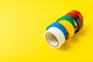 Parlak renkli arka plandaki bant yalıtılıyor. Farklı renkte izolasyon bantları. Yalıtım bandı. İnşaat aletleri. Elektrikçi aletleri. Bir parça koli bandı. Metin için boşluk. Boşluğu kopyala.