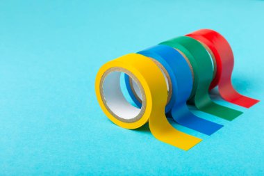 Parlak renkli arka plandaki bant yalıtılıyor. Farklı renkte izolasyon bantları. Yalıtım bandı. İnşaat aletleri. Elektrikçi aletleri. Bir parça koli bandı. Metin için boşluk. Boşluğu kopyala.