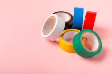 Parlak renkli arka plandaki bant yalıtılıyor. Farklı renkte izolasyon bantları. Yalıtım bandı. İnşaat aletleri. Elektrikçi aletleri. Bir parça koli bandı. Metin için boşluk. Boşluğu kopyala.