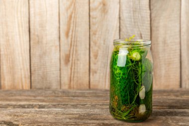 Ahşap bir arka planda kavanozda taze tuzlanmış ev yapımı salatalıklar. Dereotlu, sarımsaklı ve biberli salatalık turşusu. Konserve salatalık, salatalık ve penis. Ev yapımı koruma..