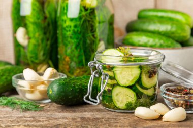 Ahşap bir arka planda kavanozda taze tuzlanmış ev yapımı salatalıklar. Dereotlu, sarımsaklı ve biberli salatalık turşusu. Konserve salatalık, salatalık ve penis. Ev yapımı koruma..