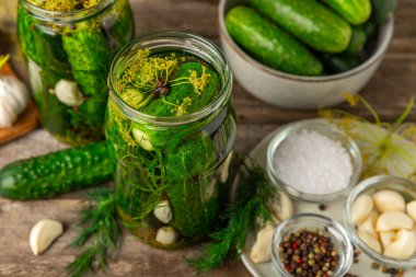 Ahşap bir arka planda kavanozda taze tuzlanmış ev yapımı salatalıklar. Dereotlu, sarımsaklı ve biberli salatalık turşusu. Konserve salatalık, salatalık ve penis. Ev yapımı koruma..