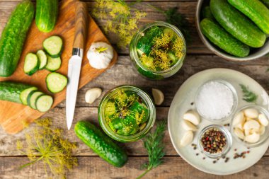 Ahşap bir arka planda kavanozda taze tuzlanmış ev yapımı salatalıklar. Dereotlu, sarımsaklı ve biberli salatalık turşusu. Konserve salatalık, salatalık ve penis. Ev yapımı koruma..