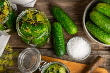 Ahşap bir arka planda kavanozda taze tuzlanmış ev yapımı salatalıklar. Dereotlu, sarımsaklı ve biberli salatalık turşusu. Konserve salatalık, salatalık ve penis. Ev yapımı koruma..