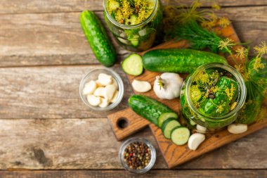 Ahşap bir arka planda kavanozda taze tuzlanmış ev yapımı salatalıklar. Dereotlu, sarımsaklı ve biberli salatalık turşusu. Konserve salatalık, salatalık ve penis. Ev yapımı koruma..