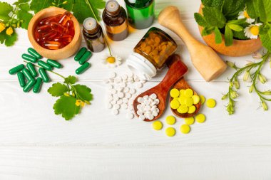Ahşap zemin üzerinde alternatif ilaç bitkisel kapsül organik ilaç. Bitki ve tablet çeşitleri, vitaminler ve diyet takviyeleri. Sağlıklı yaşam için tıbbi ve şifalı bitkiler.