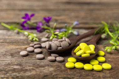 Ahşap zemin üzerinde alternatif ilaç bitkisel kapsül organik ilaç. Bitki ve tablet çeşitleri, vitaminler ve diyet takviyeleri. Sağlıklı yaşam için tıbbi ve şifalı bitkiler.