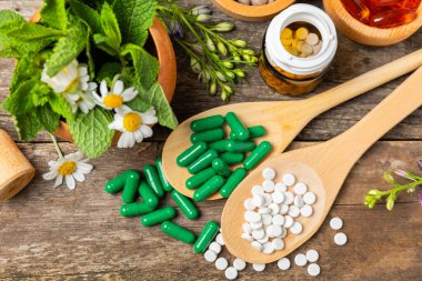 Ahşap zemin üzerinde alternatif ilaç bitkisel kapsül organik ilaç. Bitki ve tablet çeşitleri, vitaminler ve diyet takviyeleri. Sağlıklı yaşam için tıbbi ve şifalı bitkiler.