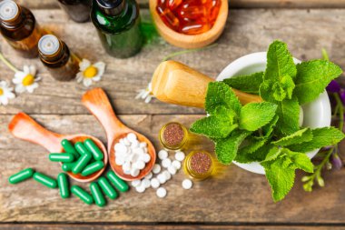 Ahşap zemin üzerinde alternatif ilaç bitkisel kapsül organik ilaç. Bitki ve tablet çeşitleri, vitaminler ve diyet takviyeleri. Sağlıklı yaşam için tıbbi ve şifalı bitkiler.