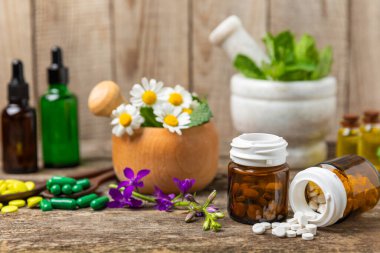 Ahşap zemin üzerinde alternatif ilaç bitkisel kapsül organik ilaç. Bitki ve tablet çeşitleri, vitaminler ve diyet takviyeleri. Sağlıklı yaşam için tıbbi ve şifalı bitkiler.
