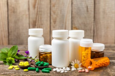 Ahşap zemin üzerinde alternatif ilaç bitkisel kapsül organik ilaç. Bitki ve tablet çeşitleri, vitaminler ve diyet takviyeleri. Sağlıklı yaşam için tıbbi ve şifalı bitkiler.